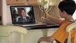 Young boy in soccer uniform video chatting with father on laptop and showing father trophy