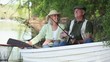 Smiling Caucasian couple fishing in rowboat on river