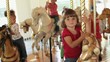 Group of smiling young girls riding carousel horses
