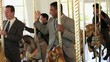 Group of smiling businessmen in suits riding carousel horses