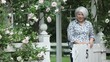 Smiling Japanese woman standing at garden gate and looking at camera