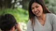 Asian boy taking photograph of smiling mother with digital camera