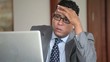 Disappointed Hispanic businessman using laptop in office