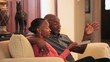 Senior Black couple watching TV on sofa in living room