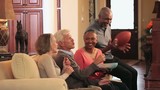 Video: Mature couples watching football on TV and eating potato chips on sofa in living room Mature couples watching football on TV and eating potato chips on sofa in living room