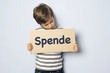 Kind ruft mit Schild zu Spenden auf
