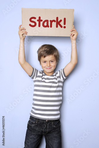 Photo: Kind hält Schild auf dem „Stark" steht Kind hält Schild auf dem „Stark" steht