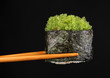 holding sushi with chopsticks isolated on black