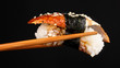 holding sushi with chopsticks isolated on black