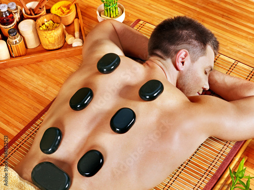 Photo: Man getting stone therapy massage . Man getting stone therapy massage .