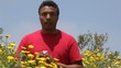 Mixed race man standing near flowers sneezing and wiping eyes