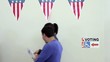 Two couples walk past a voting sign discussing ballot pamphlets