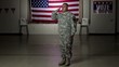 Hispanic soldier standing in front of American flag saluting