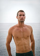 Shirtless muscular male model with sea behind