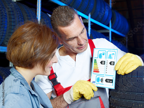 Photo: Car mechanic explains to a customer tire labeling in a garage Car mechanic explains to a customer tire labeling in a garage