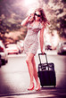 Beautiful woman with suitcases crossing the street in a big city