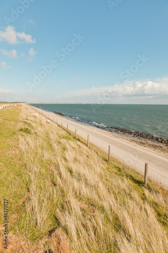 Photo: Dutch wide landscape with dike and blue cloudy sky. Dutch wide landscape with dike and blue cloudy sky.