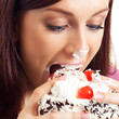 Cheerful woman eating pie, over white
