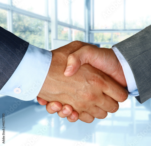 Photo: Closeup of a business hand shake between two colleagues Closeup of a business hand shake between two colleagues