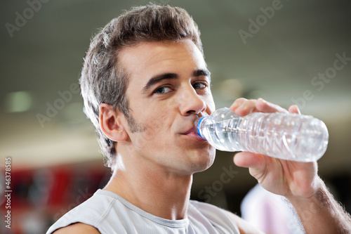 Photo: Man Drinking Water From Bottle At Health Club Man Drinking Water From Bottle At Health Club