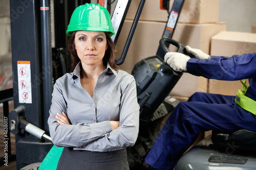 Photo: Confident Female Supervisor With Forklift Driver At Warehouse Confident Female Supervisor With Forklift Driver At Warehouse