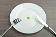 diet concept. one pea on an empty white plate