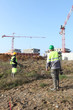 Field workers with cranes in the background