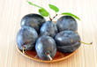 Photo: Rip plums on basket on wooden table Rip plums on basket on wooden table