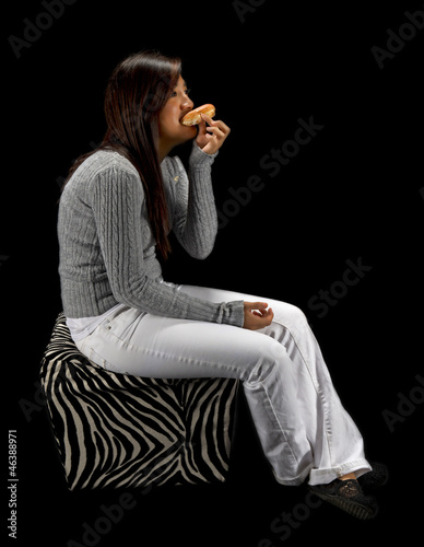 Photo: Teen girl eating a donut isolated on a black Teen girl eating a donut isolated on a black