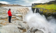 Woman standing near famous Dettifoss waterfall in Iceland