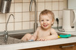 happy boy plays in the kitchen sink