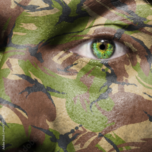Photo: Camouflage painted on a face with green eye Camouflage painted on a face with green eye