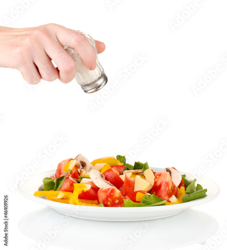 Photo: Hand adding salt using salt shaker isolated on white Hand adding salt using salt shaker isolated on white