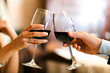 Male and female hands toasting wine glasses.