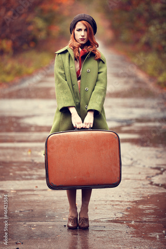 Photo: Style redhead girl with suitcase at beautiful autumn alley. Style redhead girl with suitcase at beautiful autumn alley.
