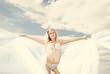 Young blond woman in white dress on background of the sky