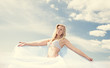 Young blond woman in white dress on background of the sky