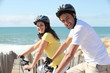 young couple riding near seafront
