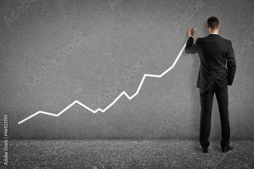 Photo: young businessman drawing trend chart on wall young businessman drawing trend chart on wall