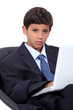 boy in an adult business suit with a laptop computer