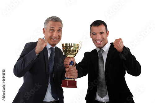 Photo: cheerful businessmen holding a golden cup cheerful businessmen holding a golden cup