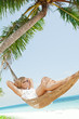 Foto: view of nice young lady swinging in hummock on tropical beach view of nice young lady swinging in hummock on tropical beach