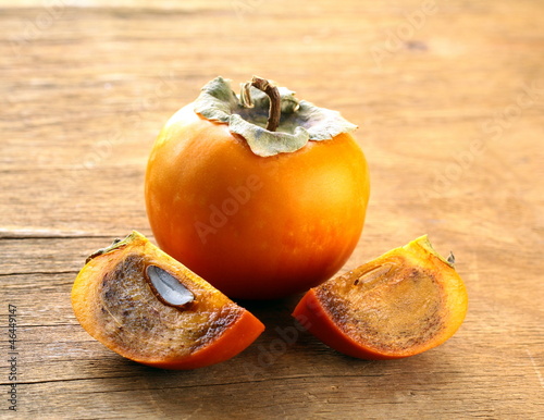 Photo: Persimmon fruit on a wooden table Persimmon fruit on a wooden table