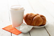 Coffee in plastic cup, sugar and croissants on a plate over wood