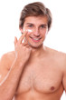 Handsome man with naked torso appliescream on his face