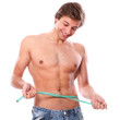 Sexy and handsome man measuring his belly after weight lose