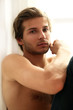 Handsome guy with naked torso sitting at the window
