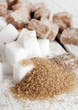 Little heap of white and brown sugar cubes on a wooden surface