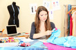 Photo: beautiful young dressmaker in workroom beautiful young dressmaker in workroom