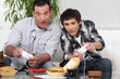 Father and son playing computer games and eating junk food